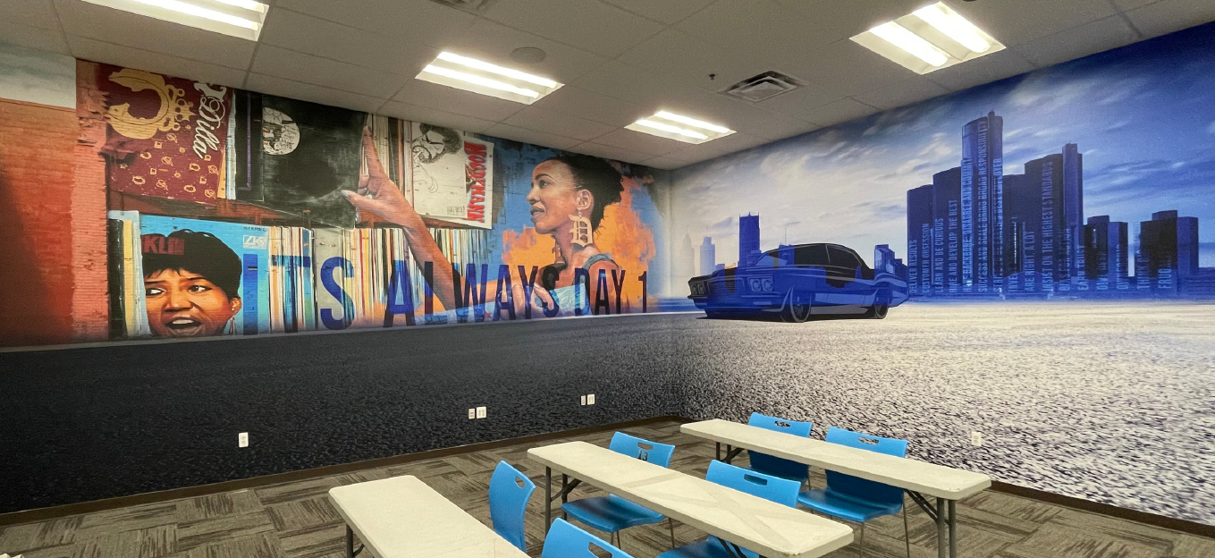 A break room with large, colorful murals depicting the local community and skyline.